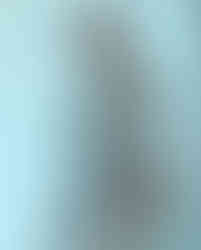 Close de Deborah Secco com expressão séria, usando capacete metálico e armadura de design robótico, revelando parte das pernas.