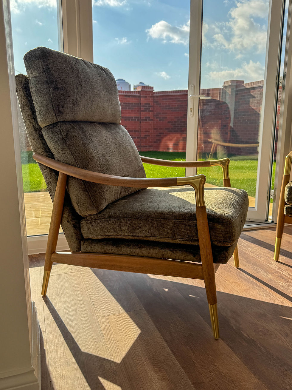 A green arm chair in a dining room with patio doors behind leading to the garden.