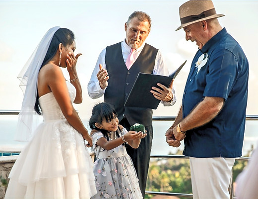 Little girl holding the wedding rings while Reverend Carter smiles