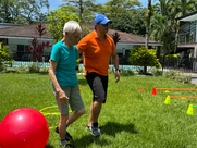 Persona mayor realiza ejercicio de equilibrio al aire libre con acompañamiento profesional