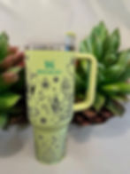 A green mug featuring a decorative flower design on its surface