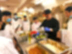 Chef prepares food in a kitchen with students