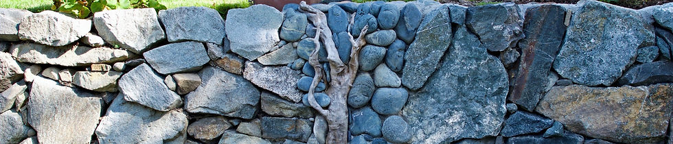A stone wall built by Lennox Masonry in Victoria, BC with river rocks and driftwood