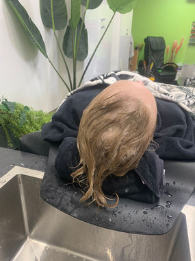Picture of client laid on the bed having her hair washed