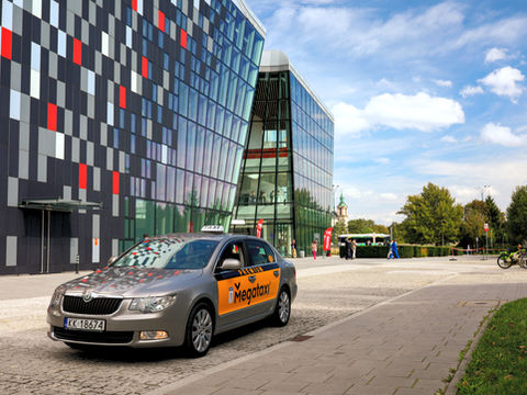 Taksówka Mega Taxi podjeżdżająca pod biurowiec w Krakowie
