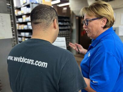 Two people talking with www.webcars.com visible on a shirt