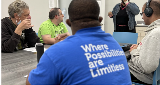 Group of people in a meeting, with text: Where Possibilities are Limitless.