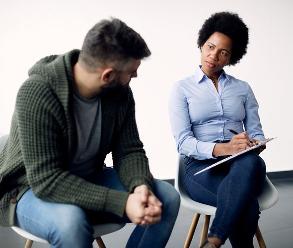 black-female-psychotherapist-taking-notes-while-talking-man-counselling.jpg