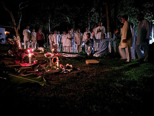 Médiuns reunidos em ritual noturno de Exús Guardiões, ao redor de altar com velas na mata