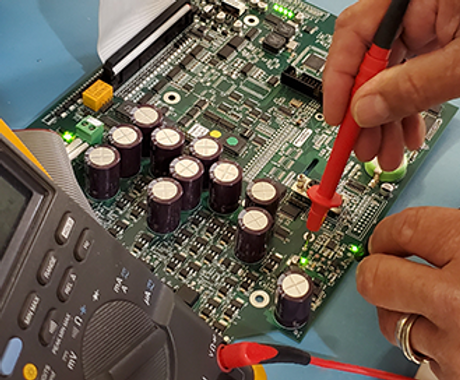 Technician using a multimeter to test a PCB with capacitors and resistors