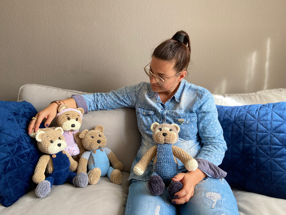 Einzigartige Stofftiere sitzen zusammen mit Petra Eichenberger auf dem Sofa.