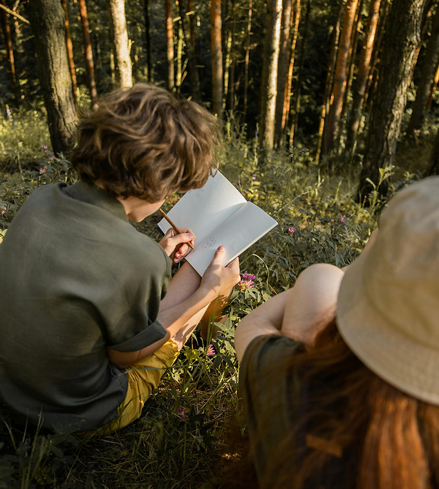 Zwei Jugendliche sitzen im Wald und machen sich Notizen