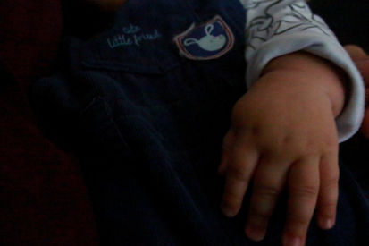 Mão de bebê em roupa azul-marinho com detalhe 'Little Friend'