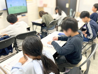 英語教室で7人の生徒がドリルに集中して取り組んでいる様子（後ろ姿）