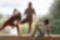 three yoga instructors doing different poses on a stone column with a grass field in the background