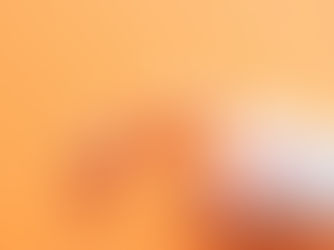 Orange and white capsules spilling from a transparent pill bottle on an orange surface. Some capsules have dosage text visible.