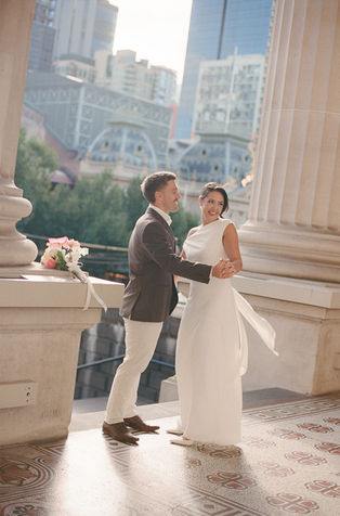 Abby and Andy on the steps of Parliament House at sunset after their Melbourne elopement on film