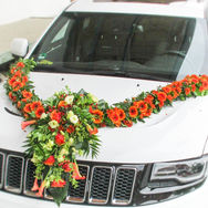 Farbenfroher Blumenschmuck für das Hochzeitsauto mit roten und orangefarbenen Blumen – Brautauto Floristik Dorfen