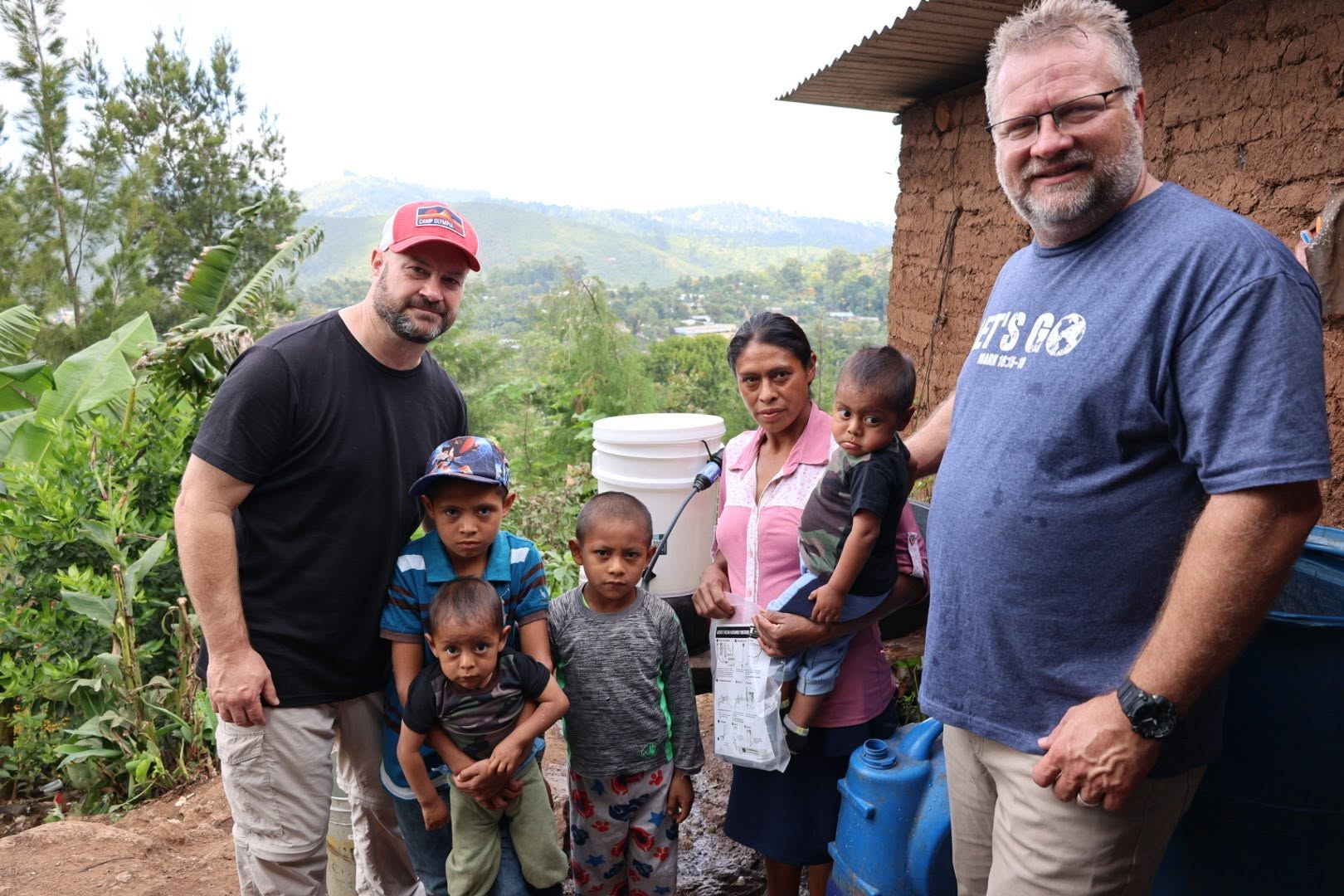Poverty Solutions clean water mission team with a family and children beside a water filtration bucket