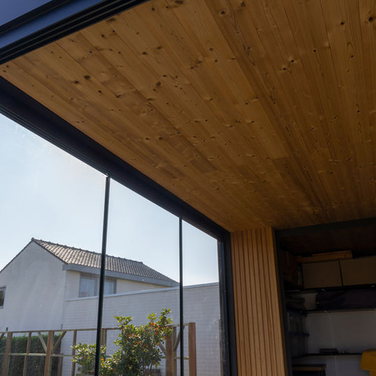 Zwart aluminium Maluwi frame met houten zijwanden voor een gezellige buitenlounge.