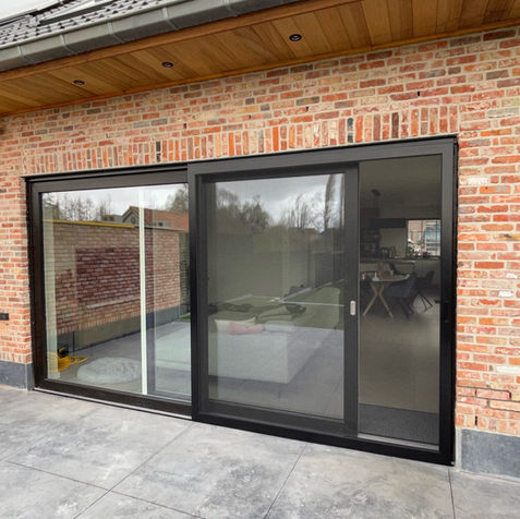 Maatwerk schuifvliegenraam met robuust zwart gaas geplaatst voor een grote schuifpui in Waasmunster door Zonwering-winkel.