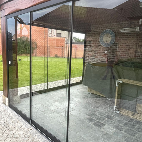 Transparante glazen schuifwand met minimalistische profielen geplaatst als terrasafsluiting in Hamme door Zonwering-winkel.
