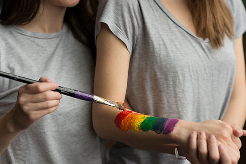primer-plano-de-una-mujer-joven-pintando-la-bandera-de-lbgt-sobre-la-mano-de-su-novia-con-