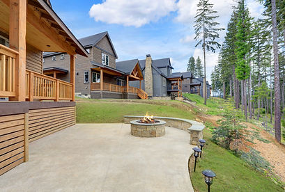 Beautiful wooden back porch with chairs on the hill and large backyard patio with fire pit