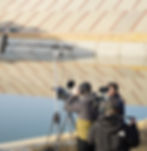 Film crew with camera and boom mic filming outdoors by a canal