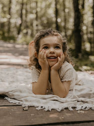 Ein lächelndes Mädchen liegt auf einer Decke im Wald, Jasmin Schweizer Photography.