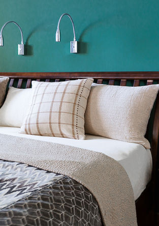 ein Bett mit Kissen und einer Decke vor einer grünen Wand