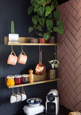 ein Regal mit Marmeladengläsern und Kaffeetassen darauf