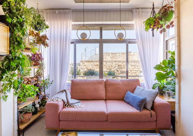 ein Wohnzimmer mit einer rosa Couch und vielen Pflanzen