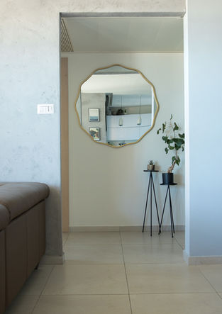 ein Wohnzimmer mit einer Couch und einem Spiegel an der Wand