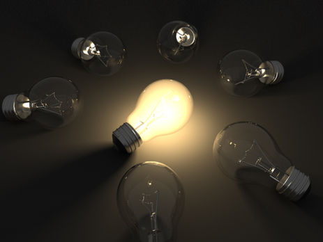 a lit lightbulb surrounded by unlit bulbs