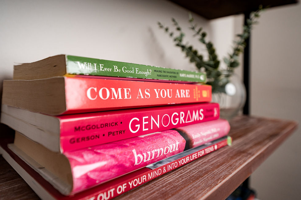 spines of books about sexual health, family relationships, and mental health on a shelf next to plant leaves.