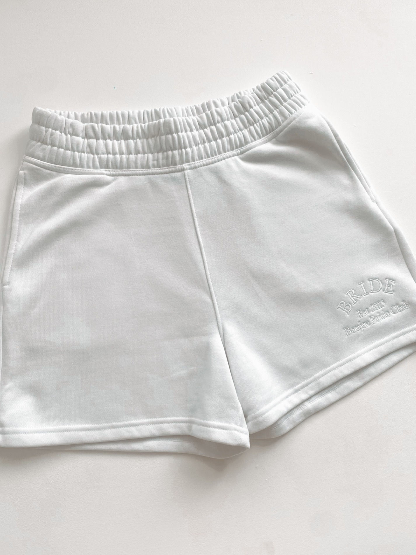 White elasticated shorts with a small embroidered logo on the leg