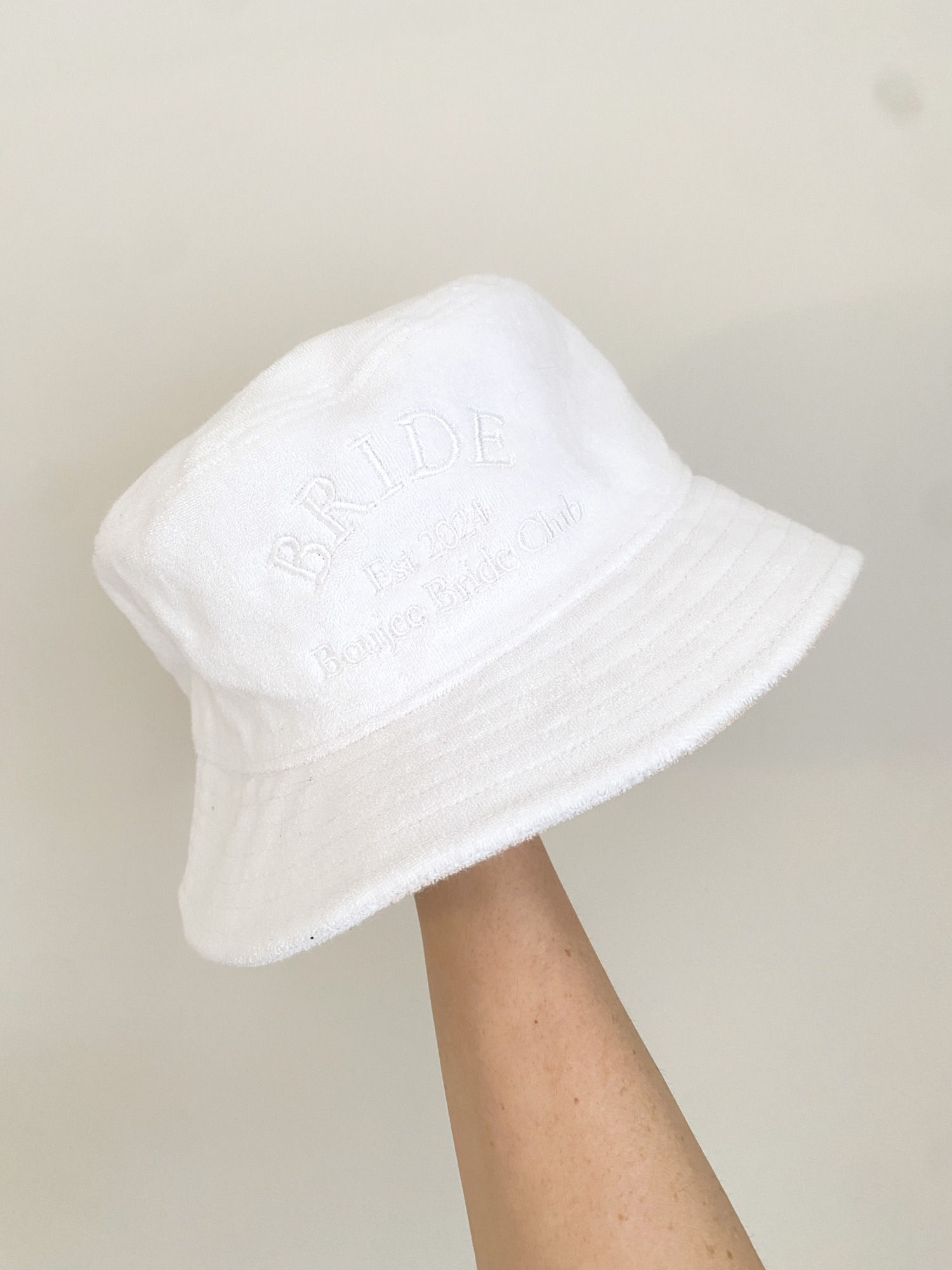 A white bucket hat with a white embroidered design on the front