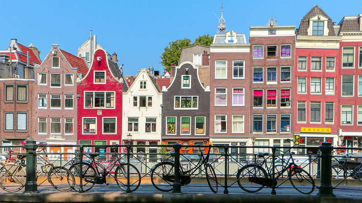 Quaint and colorful canal houses line a bustling street in Amsterdam