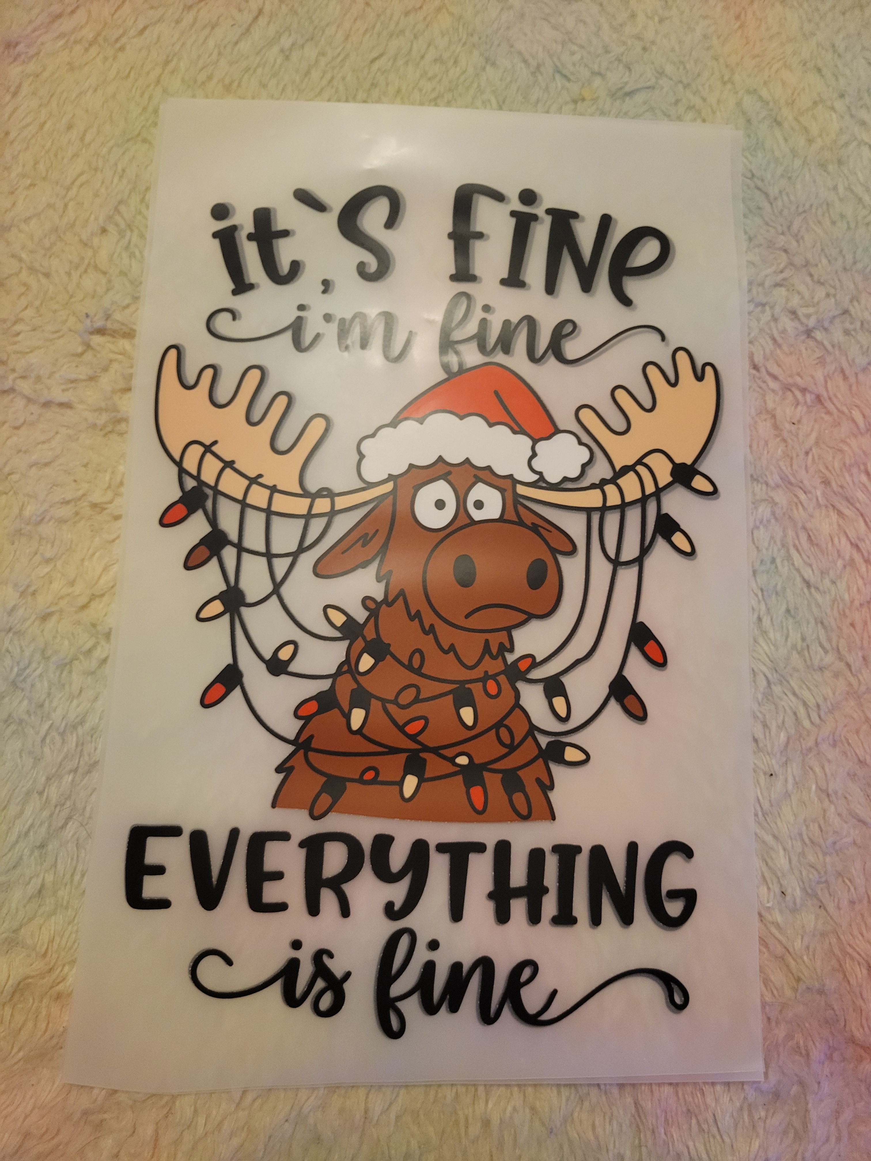 Cartoon moose tangled in Christmas lights, text "it's fine"