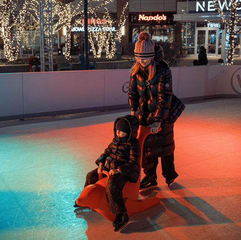 Family ice skating under colorful Christmas lights in Lincoln Park, Chicago at Wonder City.