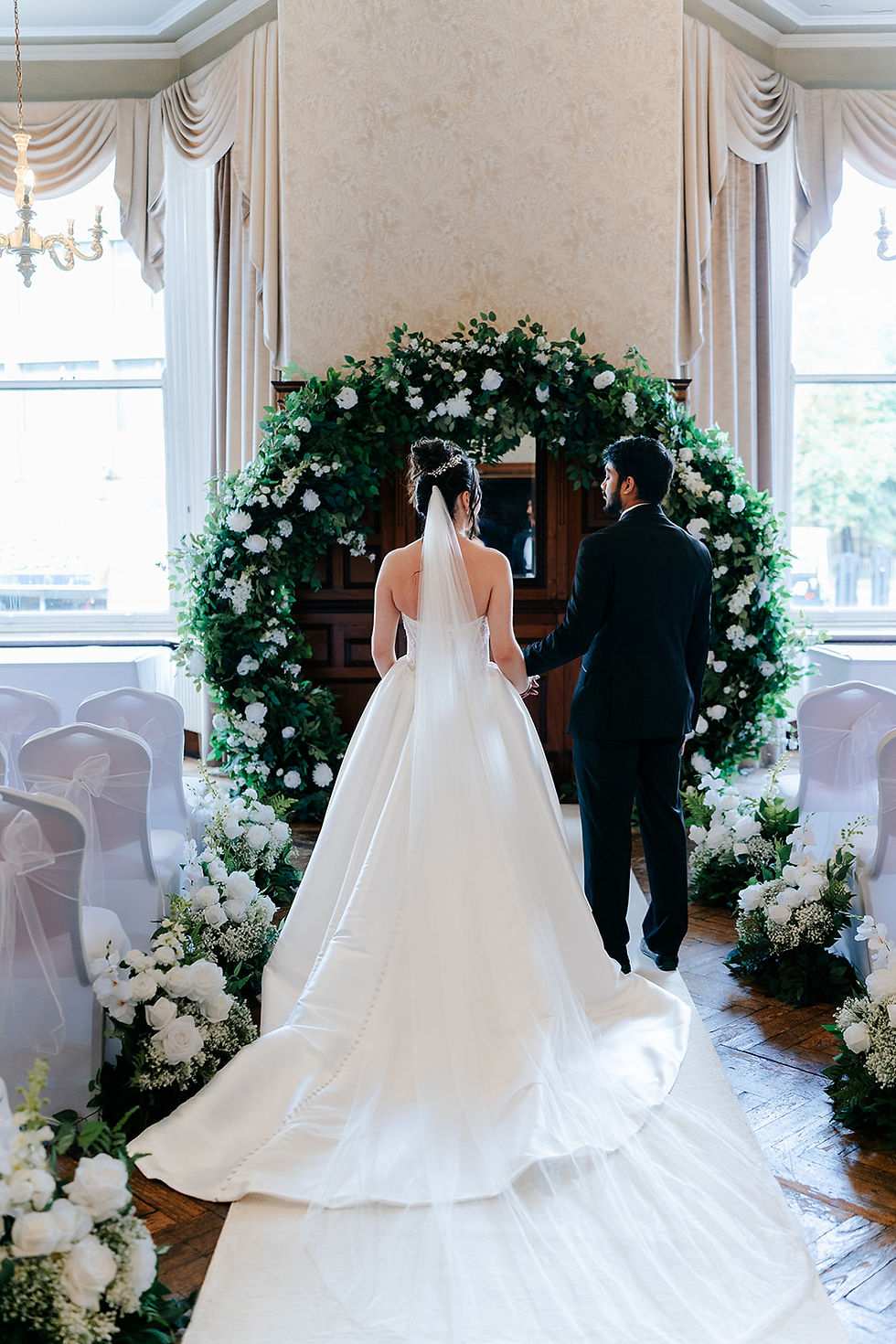 Bride and groom walking down aisle with flower meadows and arch