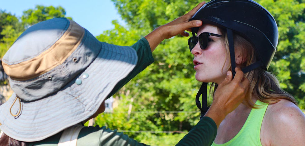 Guide Carla adjusts a guest's helmet before a safe horseback riding tour near San Ignacio