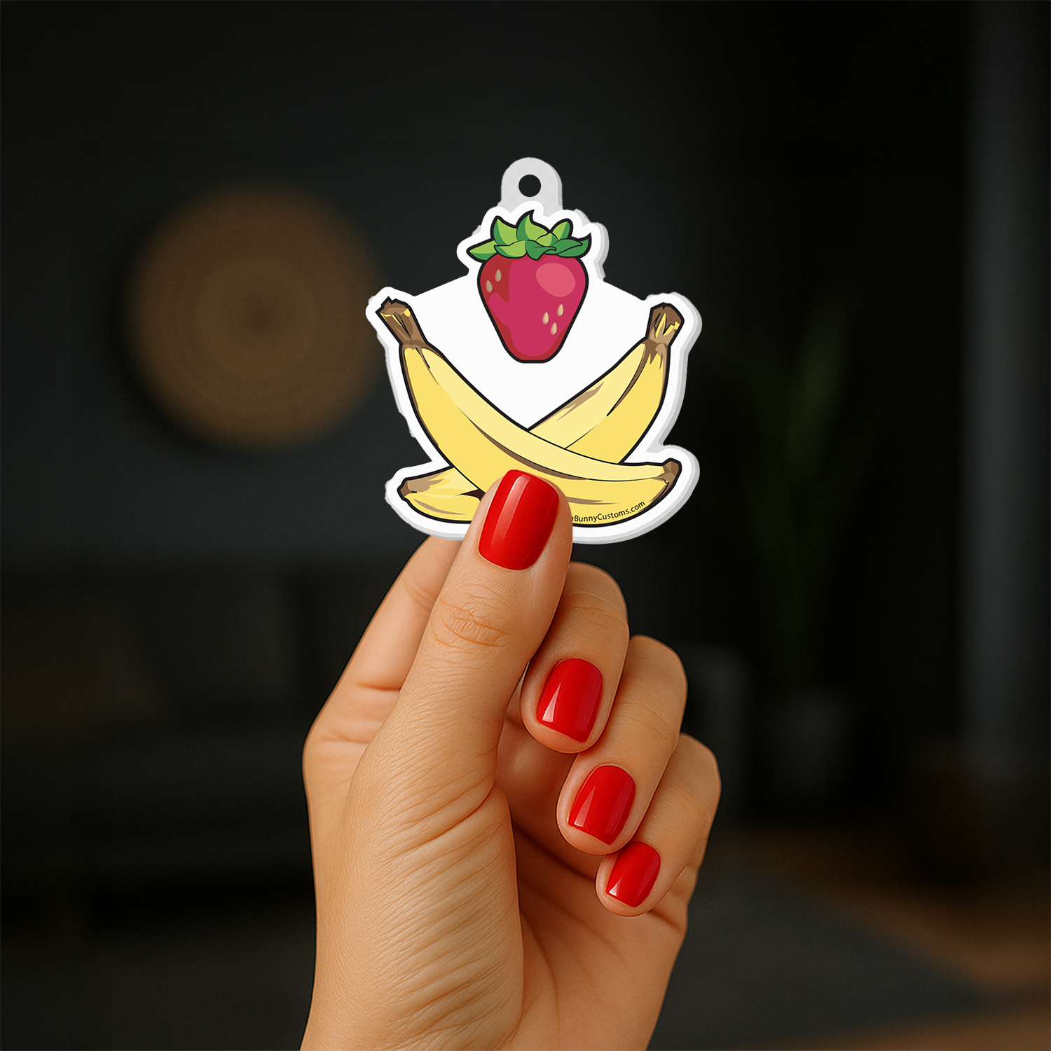 Strawberry and Cross-Bananas Keychain in hand with red nail polish