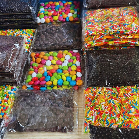 Schokolinsen, Schokostreusel, bunte Linsen und bunte Streusel abgepackt auf einem Tisch