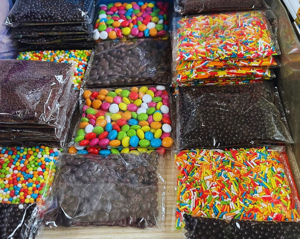 Schokolinsen, Schokostreusel, bunte Linsen und bunte Streusel abgepackt auf einem Tisch