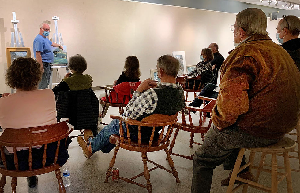 group of people in chairs looking at a painting