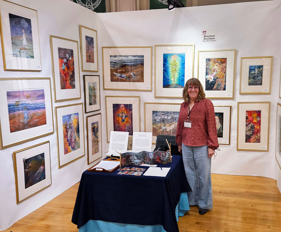 a woman standing in her art booth at an art fair