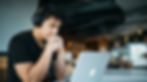 man wearing headphones while sitting on chair in front of MacBook_edited.jpg
