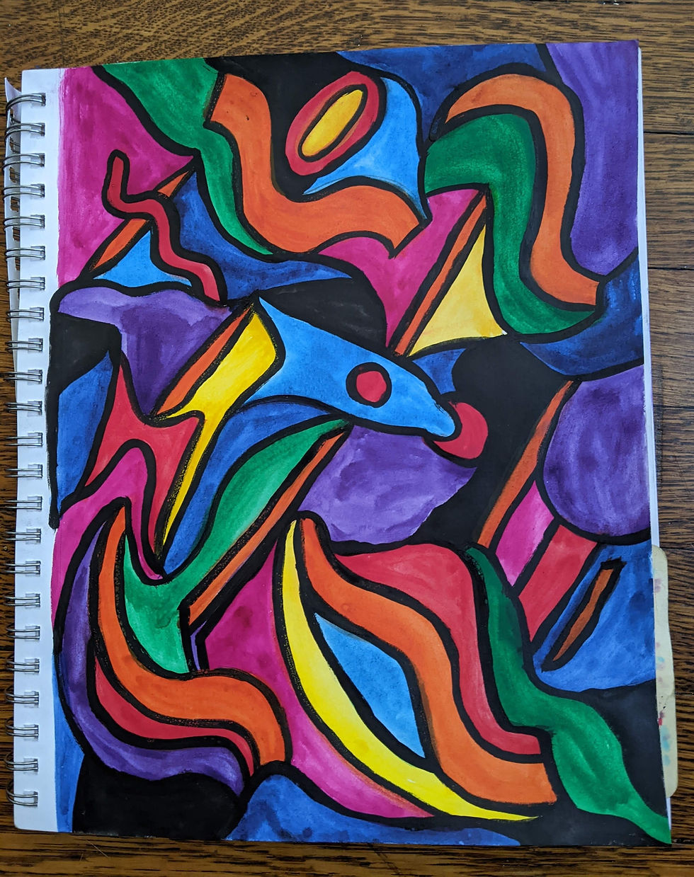 A sketchpad on the ground with many squiggly lines and multicolored shapes.